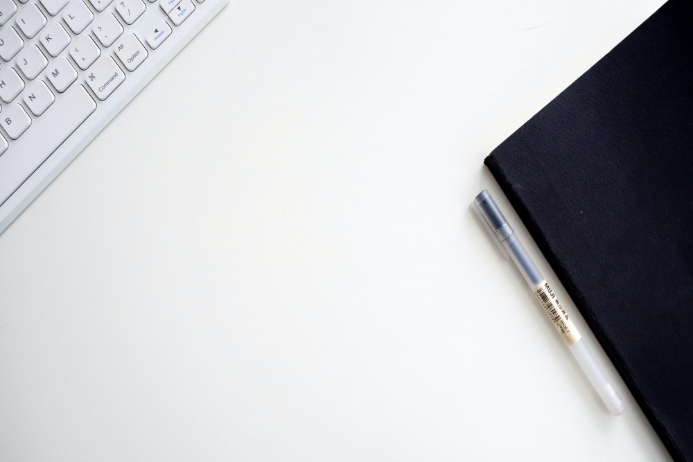 white keyboard and balck note book on table