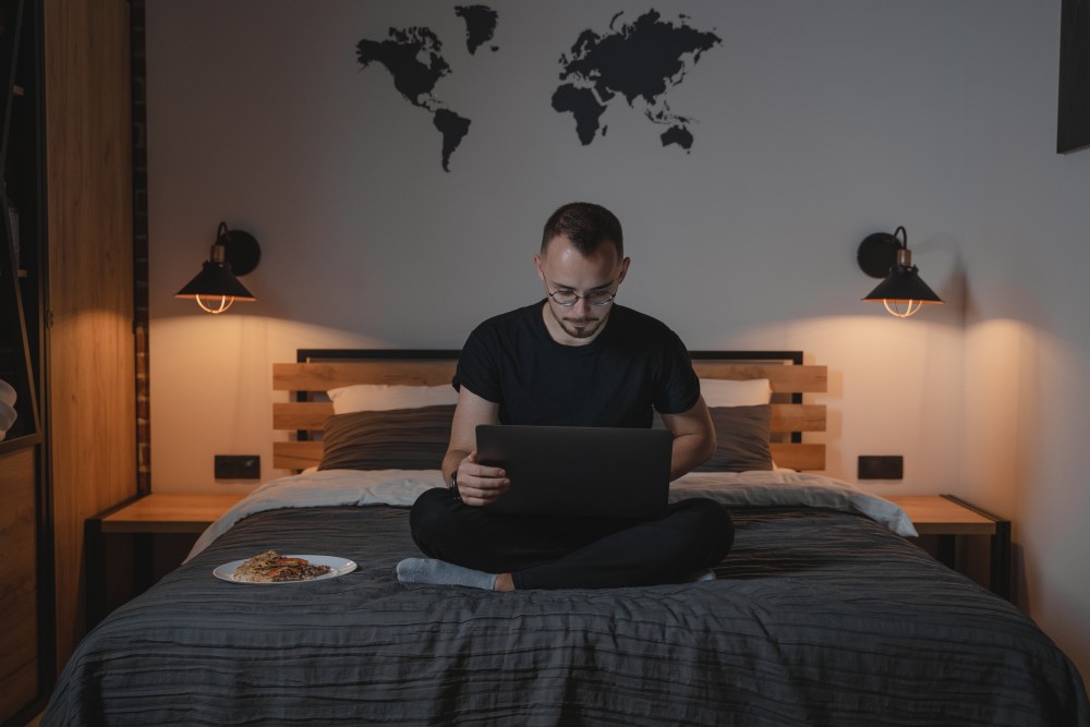 young man sitting in his room working on laptop